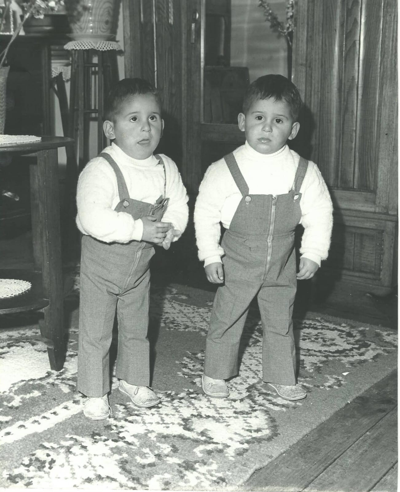 An early black-and-white family photograph of two small children in matching dungarees