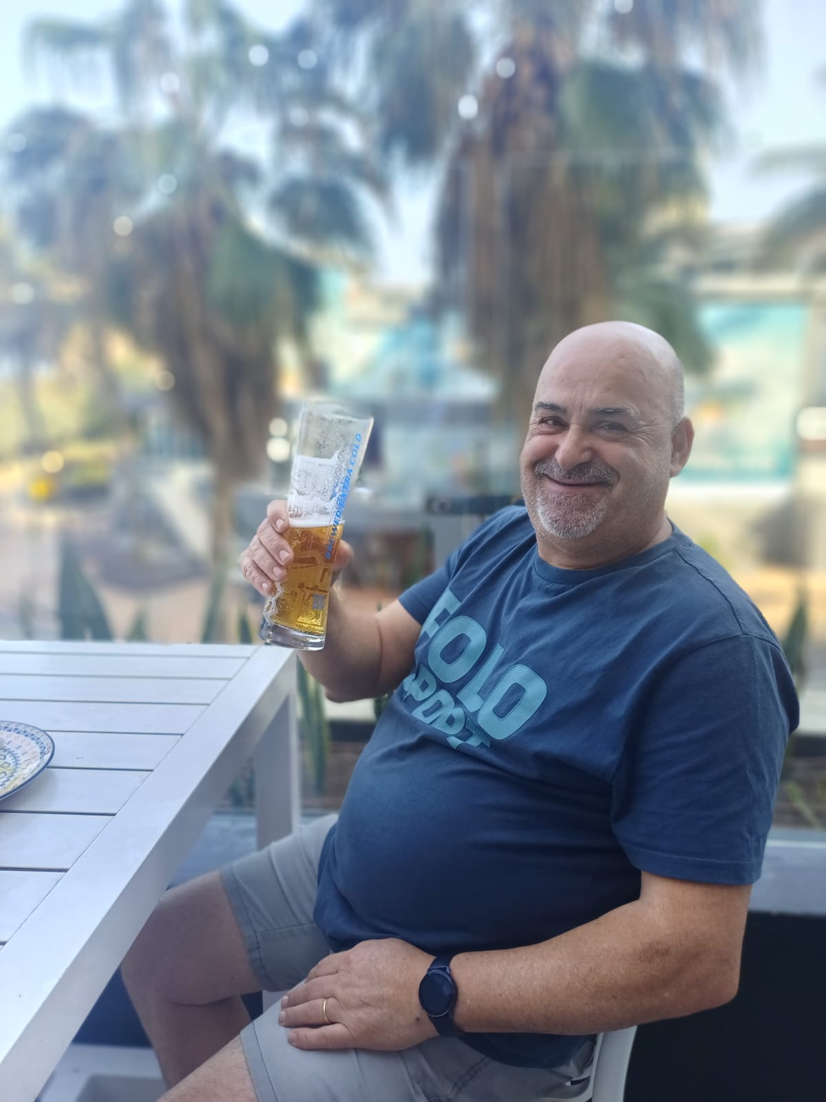 Dad smiling and raising a beer at an outdoor table