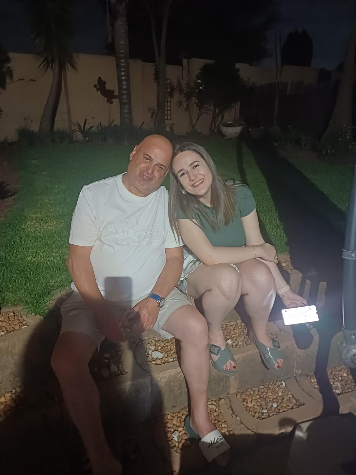 Dad and a family member smiling together in the garden at night