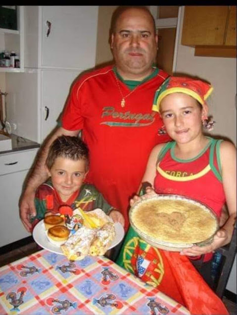 Dad standing with two children in a kitchen as they hold plates of food