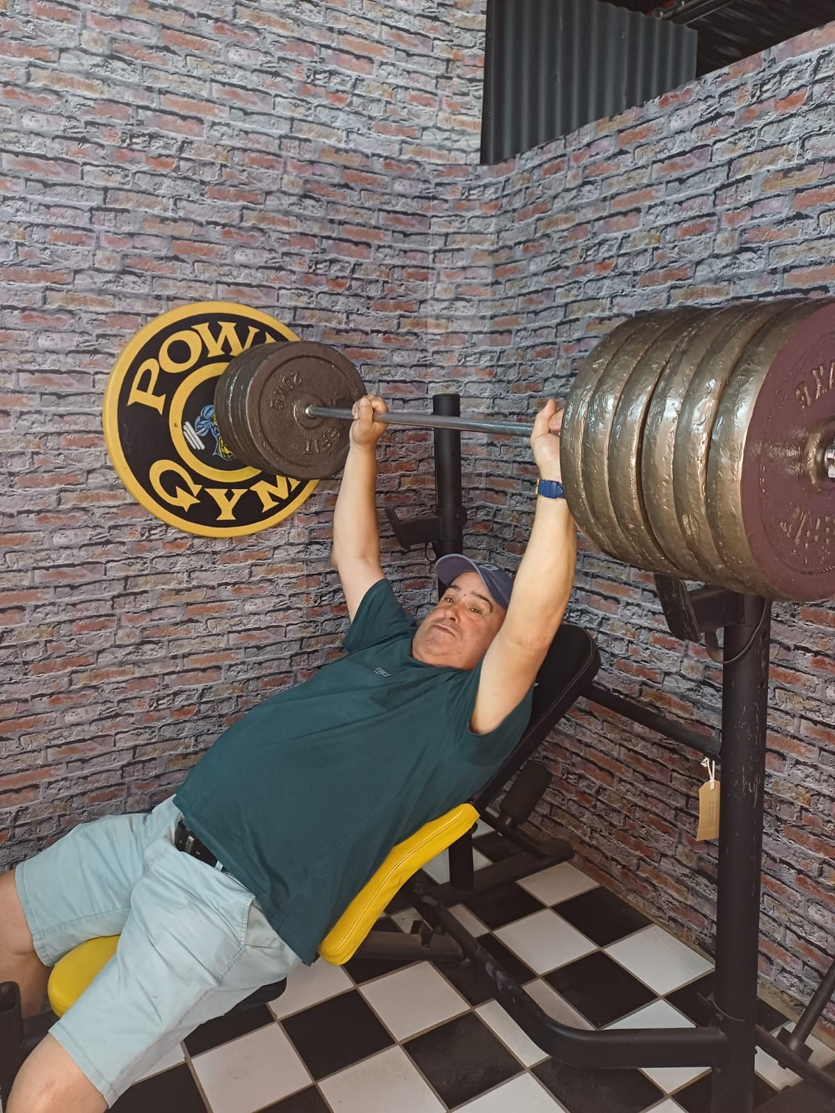 Dad playfully posing beneath an oversized barbell display