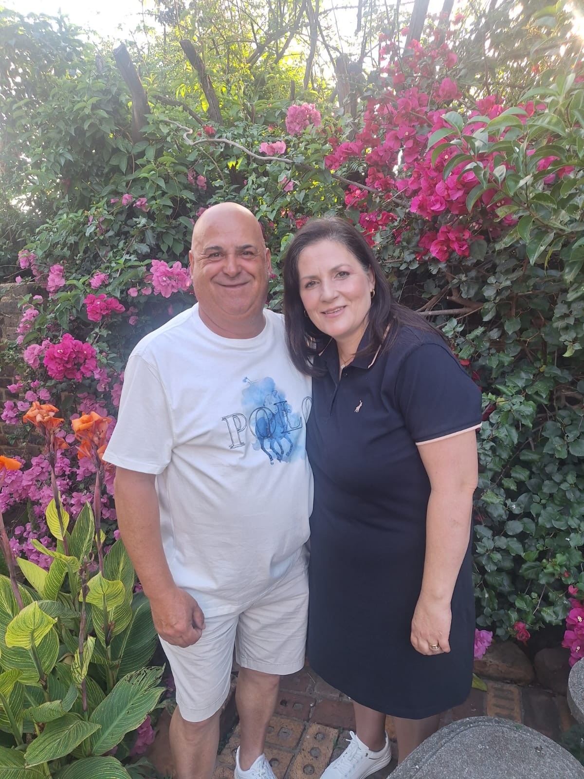 Dad and his partner smiling together beside pink flowers